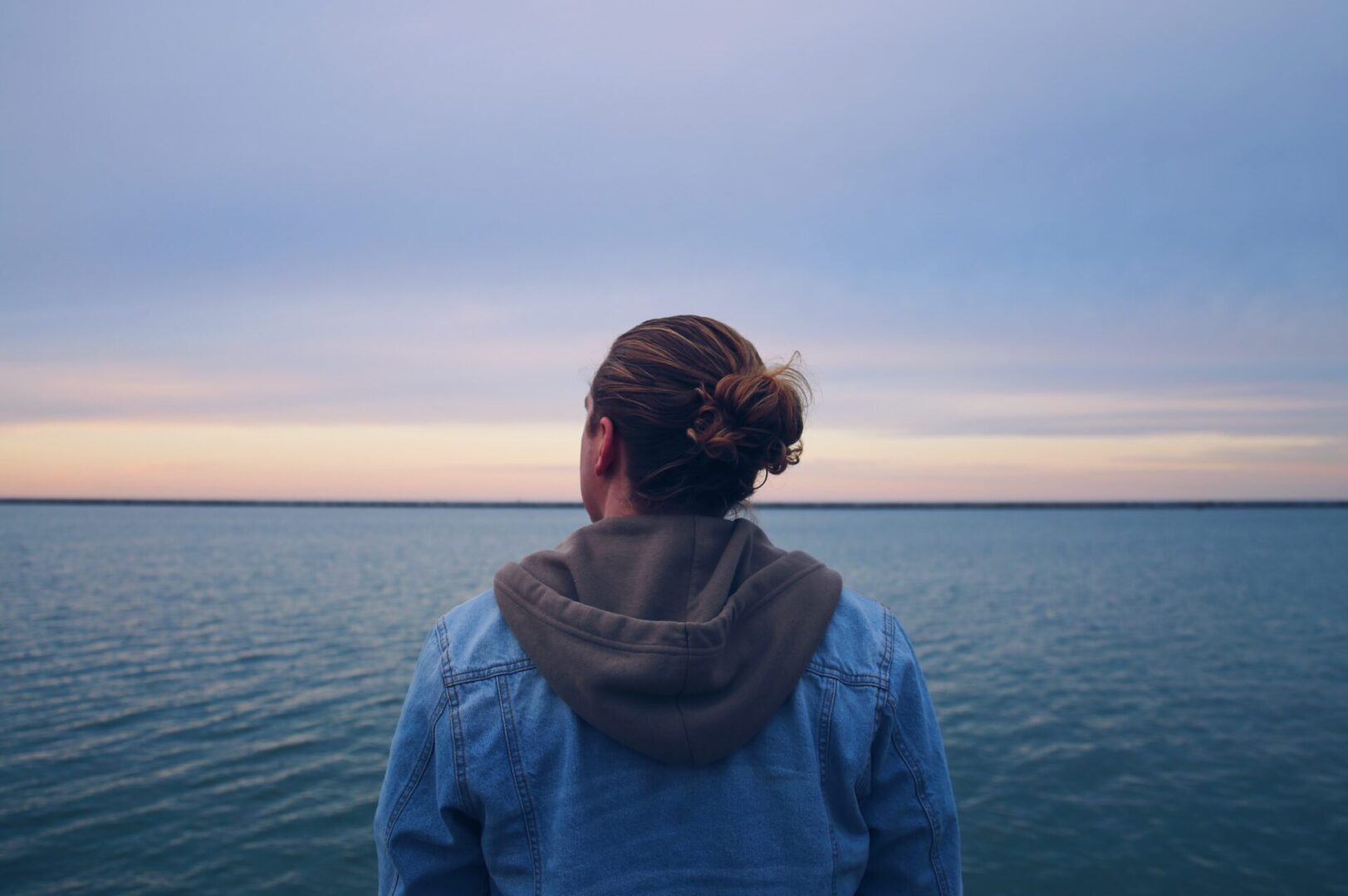 A person standing in front of the ocean looking out at the water.