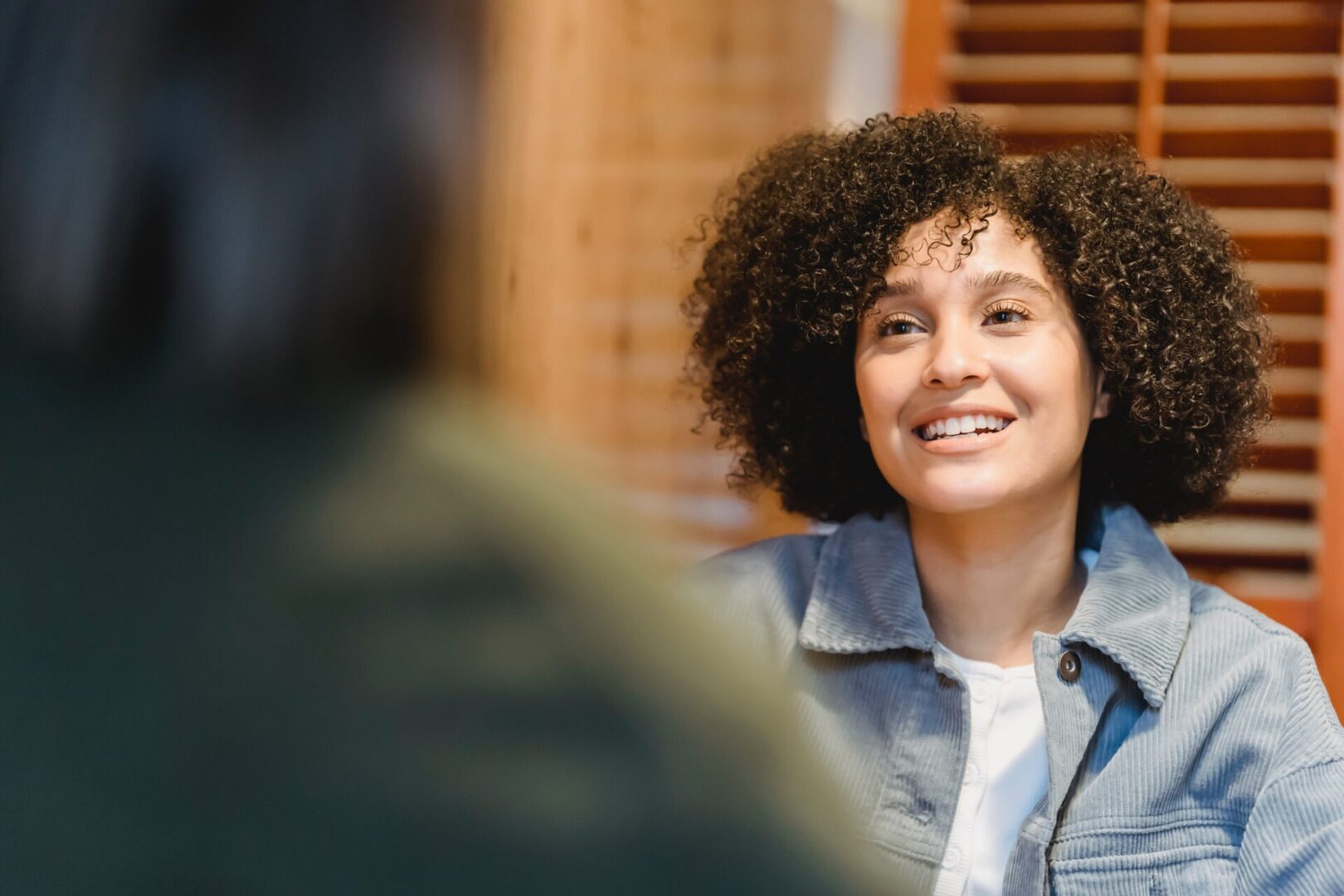 A woman with curly hair smiling at the camera.